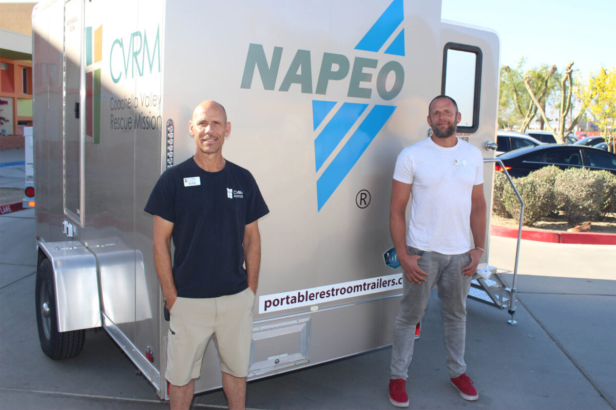 Two men standing in front of NAPEO branded trailer