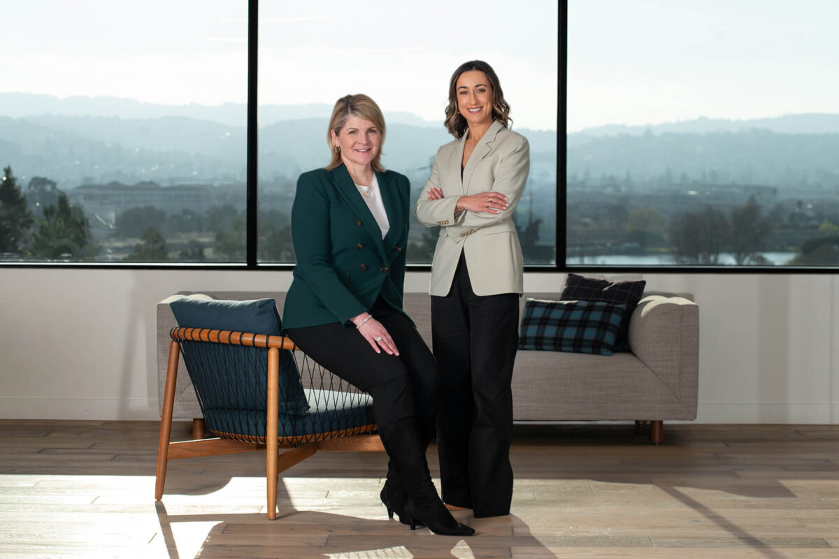 Kathy Ross and Christina Sullivan, poised in front of a large window.