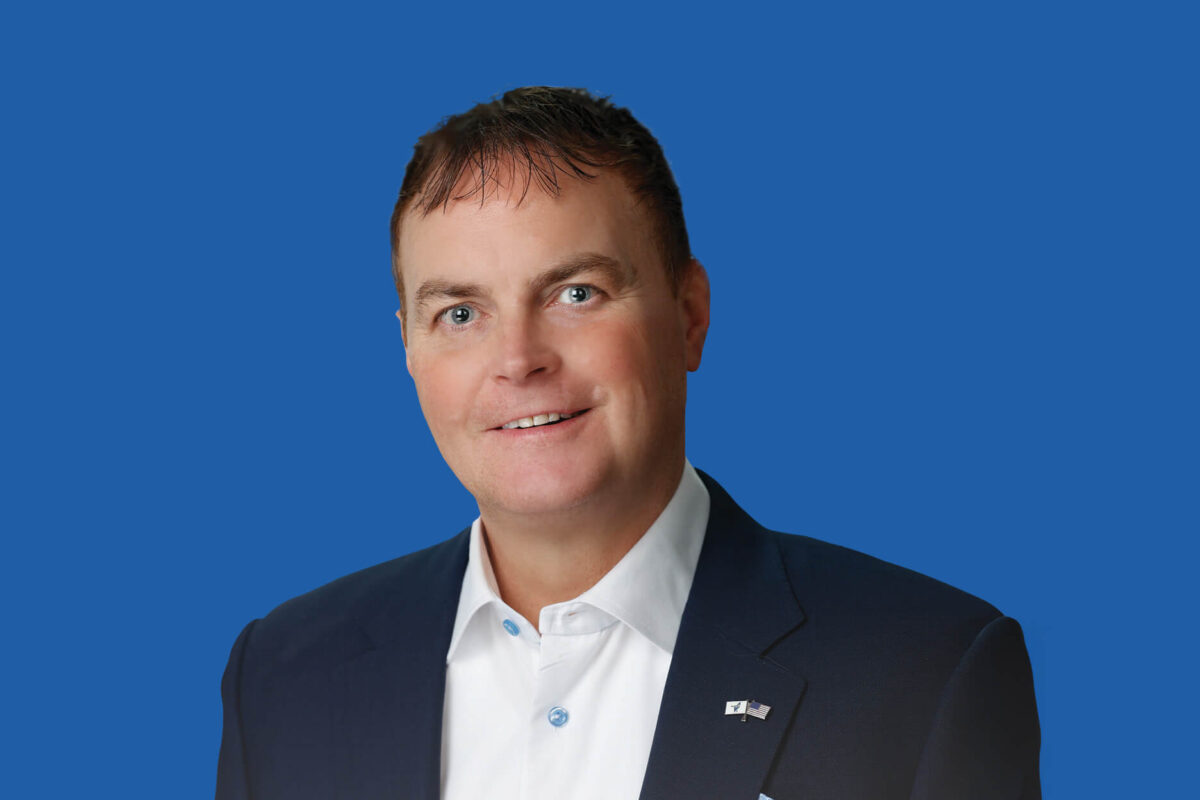 Headshot of Tim Graham with blue background.