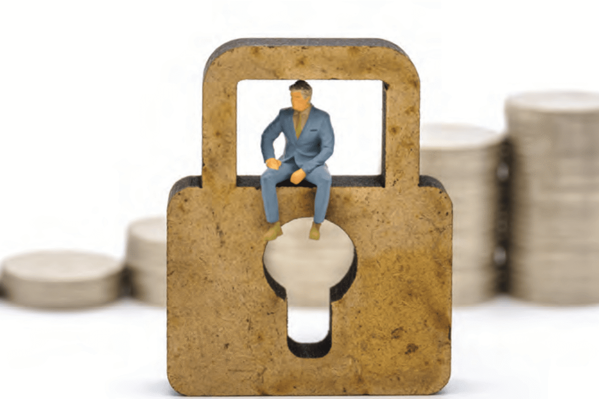 Illustration of a businessperson sitting inside the opening of a large padlock above a keyhole.